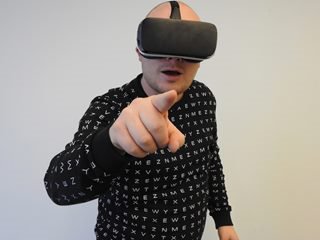 person wearing a VR headset pointing their finger at the camera