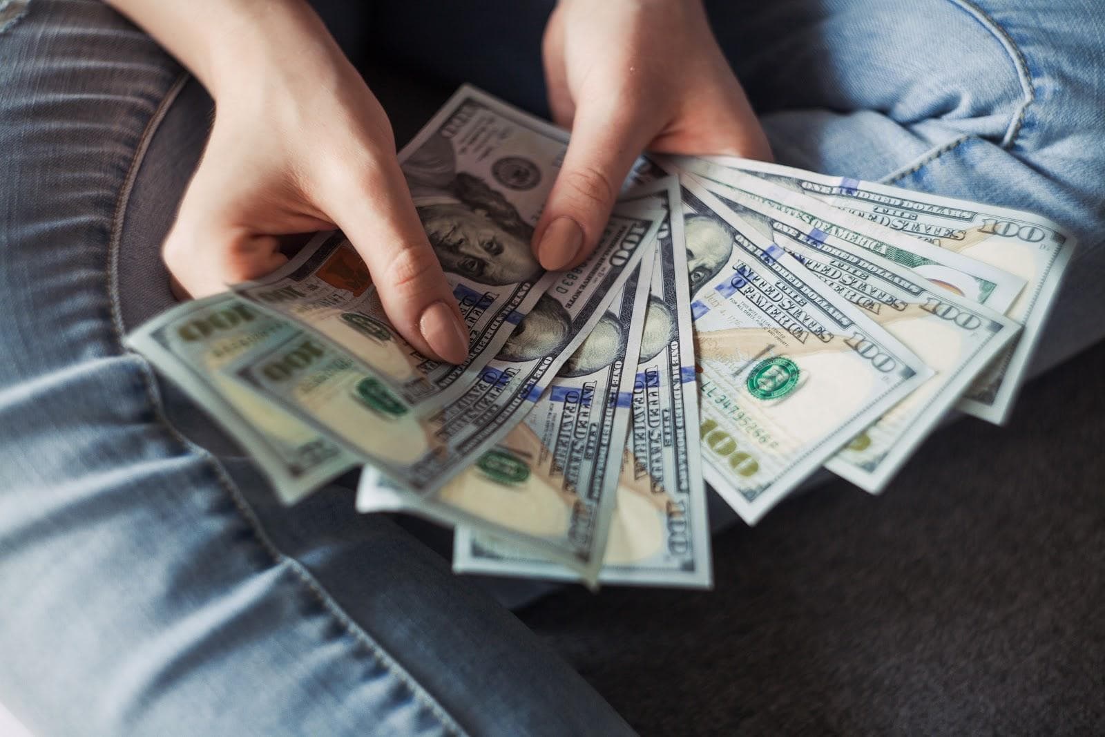 Person holding stack of dollar bills