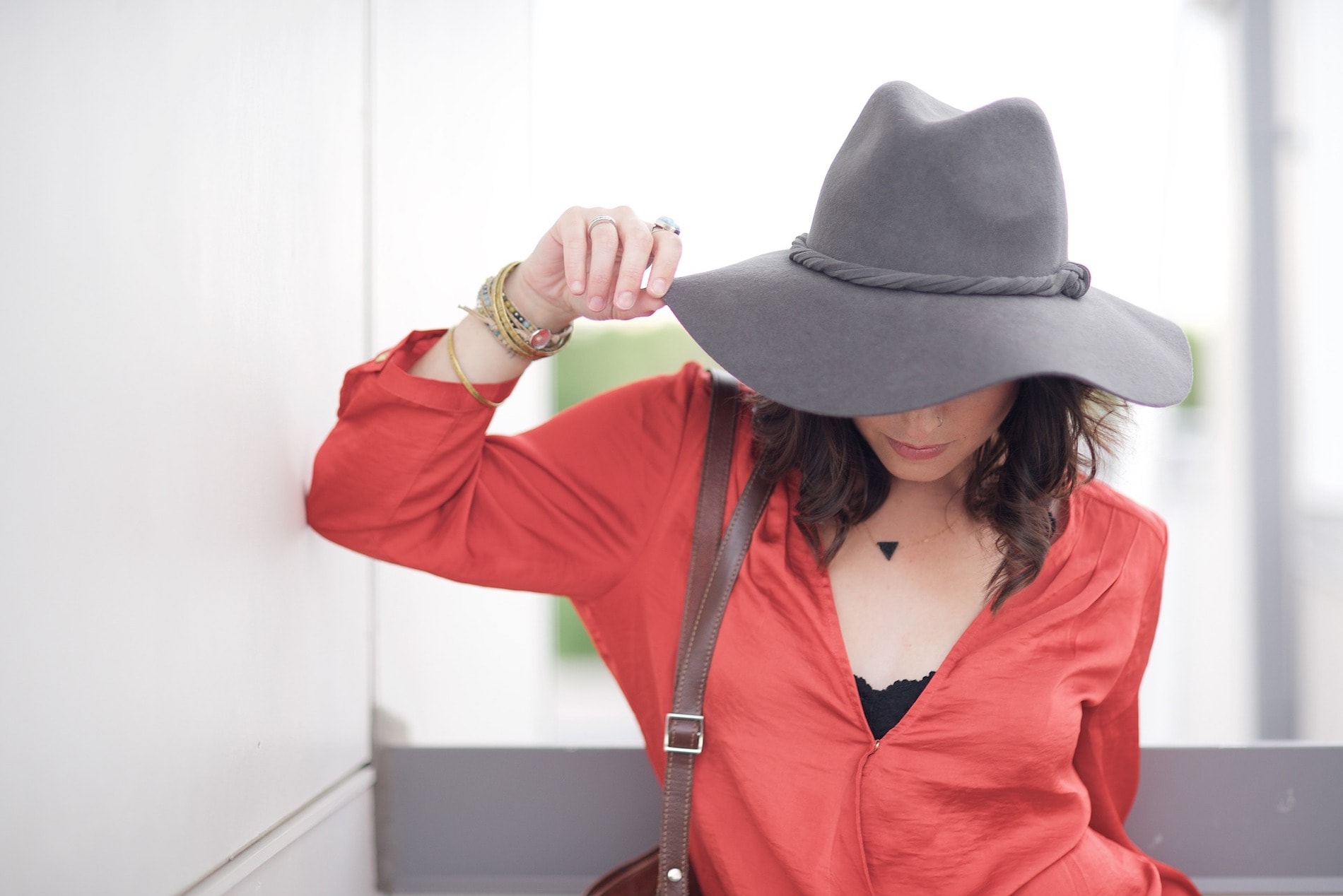 Model looking down wearing a red dress and wide-brimmed hat